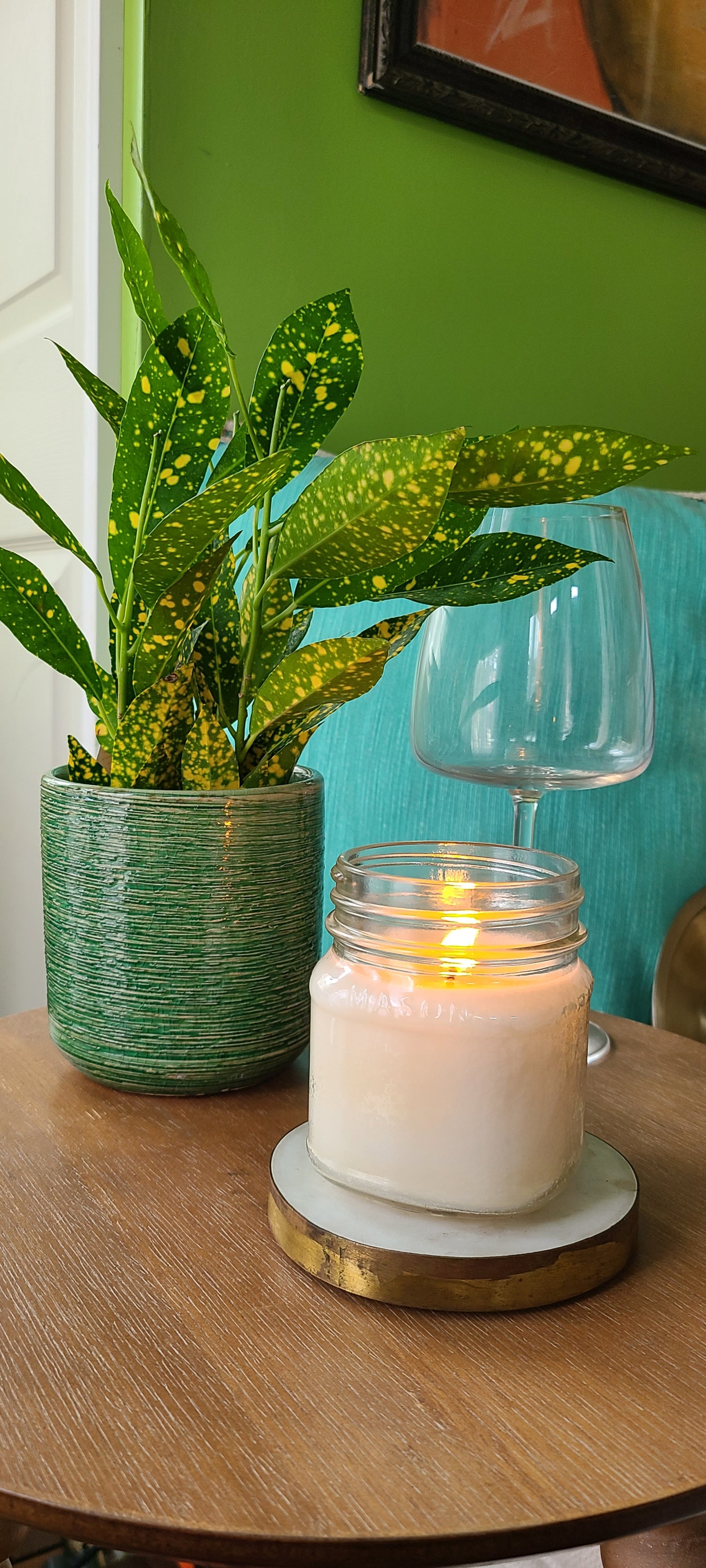 Ella Belle Candle Co. Mason Jar Candle lit with plant and wine glass in the background.