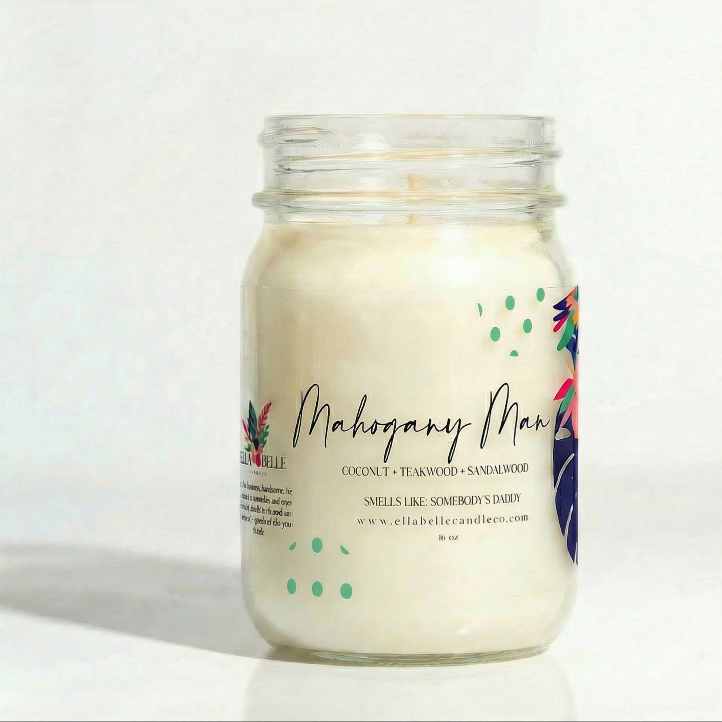 Candle in a glass jar with a colorful label  with "Mahogany Man" on a white background

