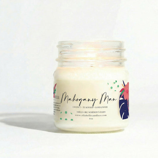 Candle in a glass jar with a colorful label  with "Mahogany Man" on a white background
