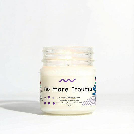 Candle jar labeled 'no more trauma' on a white background