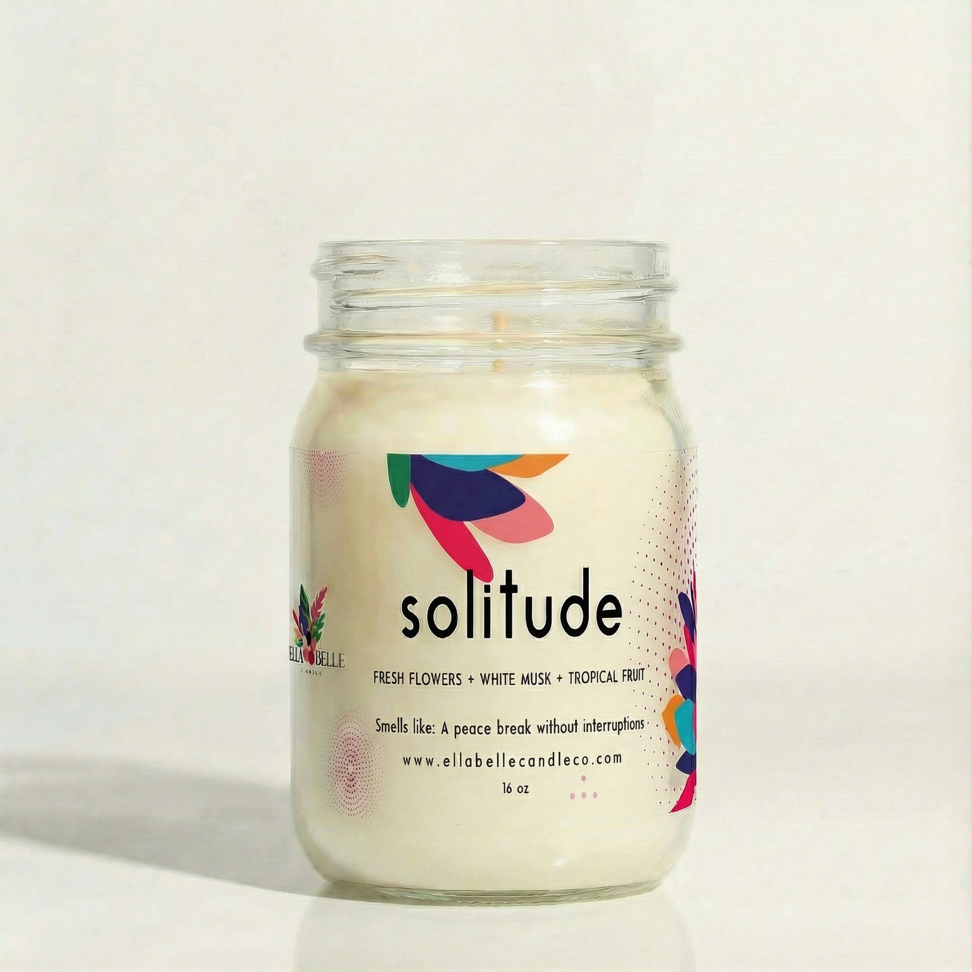 Candle jar labeled 'solitude' with colorful design on white background