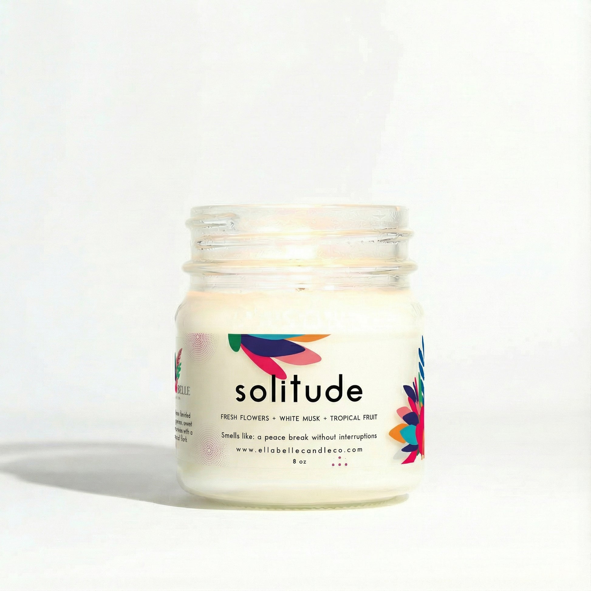 Candle jar labeled 'solitude' with colorful design on a white
background