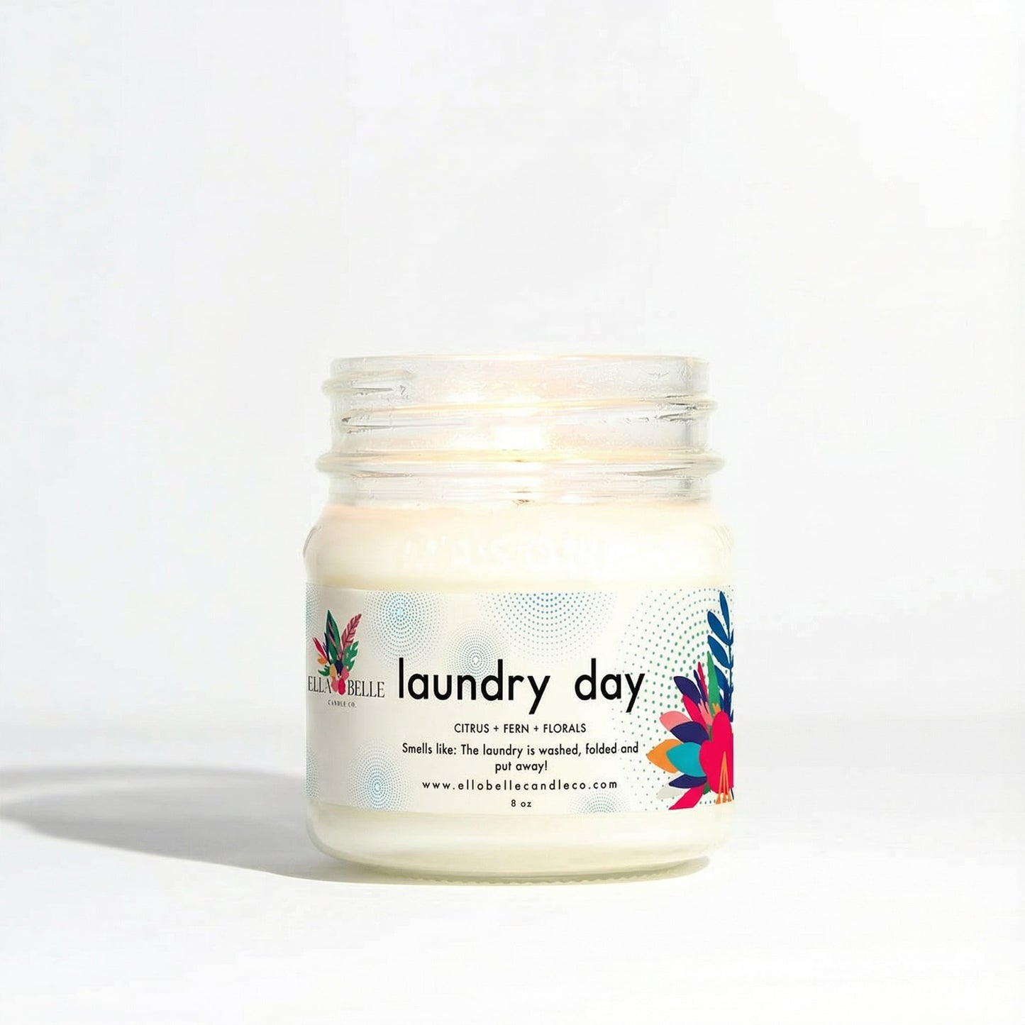 Jar of candle labeled 'laundry day' with colorful design on a white background