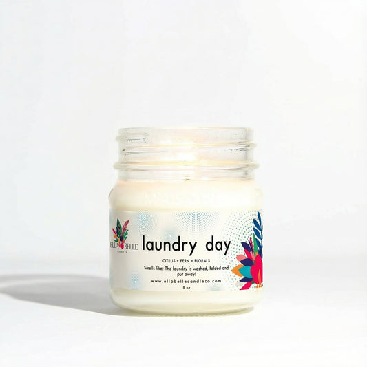 Jar of candle labeled 'laundry day' with colorful design on a white background