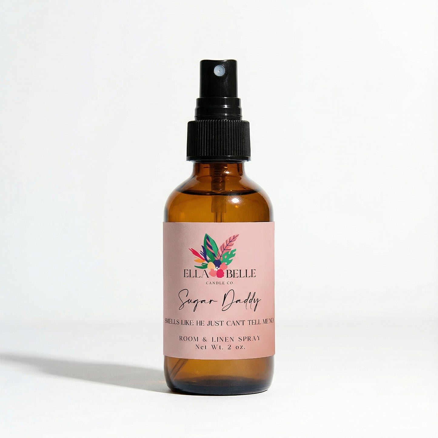 Brown glass spray bottle with a pink label on a white background