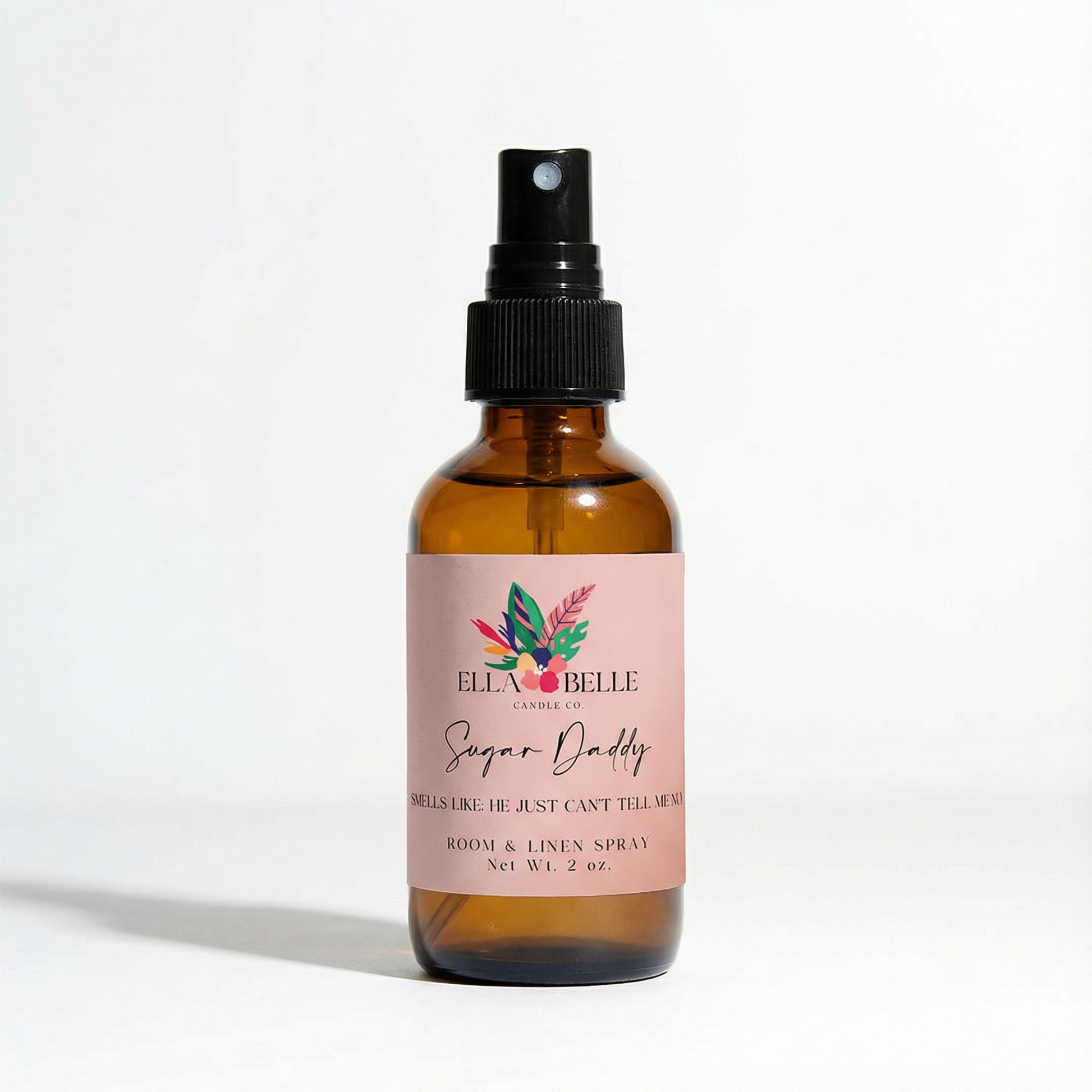 Brown glass spray bottle with a pink label on a white background
